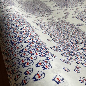 May include: White fabric with a repeating pattern of blue and red cartoon bears wearing bow ties. The bears are arranged in rows and columns.