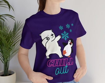 May include: A purple t-shirt featuring a cartoon polar bear and penguin with snowflakes. The polar bear is dabbing, and the penguin is looking on. The words "CHILL out" are printed in pink and teal.