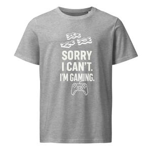 Puede incluir: Camiseta gris con un gráfico blanco que dice "Lo siento, no puedo. Estoy jugando." y un contorno blanco de un mando de videojuego.