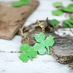 May include: A pair of green four-leaf clover earrings with gold hooks. The clovers are made of small green beads.