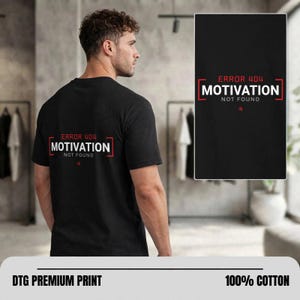 May include: A black short-sleeved t-shirt featuring the white text ERROR 404 MOTIVATION NOT FOUND enclosed in red brackets on the back. The design includes a small red character below the text. The shirt is made of 100% cotton.