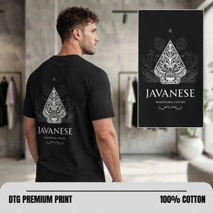 Op de afbeelding: Een zwart t-shirt met korte mouwen en een witte grafische print op de achterkant. Het ontwerp toont een gestileerde wayang kulit-popvorm met ingewikkelde patronen, de tekst JAVANESE TRADITIONAL CULTURE en een Japans teken erboven.