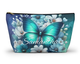 May include: A zippered cosmetic bag featuring a teal butterfly with the name "Samantha" in white script. The butterfly is surrounded by blue and white flowers against a watercolor background.