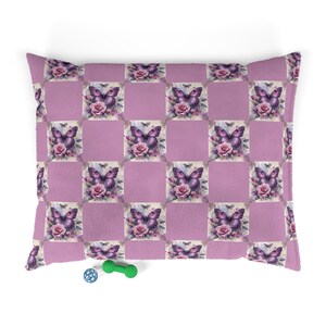 May include: A purple and pink pet bed with a checkered pattern featuring butterflies and roses. The bed is made of soft, plush fabric.