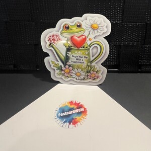 Commencez votre journée avec un sourire - Grenouille avec un coeur dans un arrosoir - Sticker en vinyle - Ordinateur portable - Bouteille d'eau - Étui pour téléphone - Cahiers
