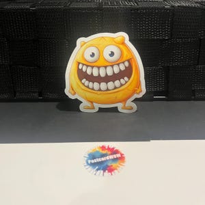 Monstre jaune avec un grand sourire - Autocollant en vinyle - Ordinateur portable - Gourde - Étui pour téléphone - Carnets