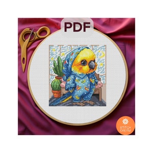May include: A cross-stitch pattern featuring a yellow and blue parakeet wearing blue pajamas with stars. The parakeet is sitting on a wooden perch in front of a window with a cactus plant.