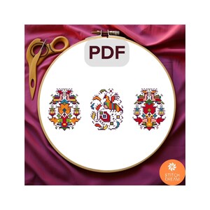 May include: Three colorful cross-stitch patterns featuring geometric designs with red, yellow, blue, green, and white colors. The patterns are displayed in a wooden embroidery hoop on a pink fabric background. The text "PDF" is displayed in a gray box on the hoop.