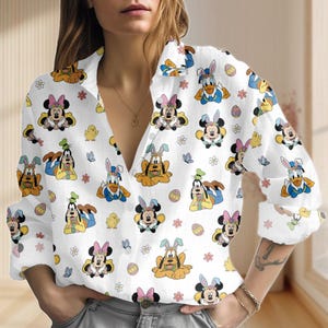 Może przedstawiać: Biała koszula zapinana na guziki z nadrukiem na całej powierzchni postaci z kreskówek przebranych za zające wielkanocne. Projekt zawiera Myszkę Miki, Minnie, Kaczora Donalda i Goofy'ego, a także pisanki i kwiaty. Koszula ma długie rękawy i kołnierzyk.