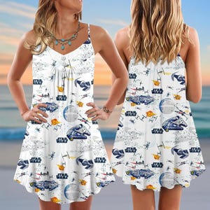 Peut inclure: Robe blanche à fines bretelles avec un imprimé Star Wars. La robe a un décolleté en V et une jupe évasée. Le motif Star Wars comprend des vaisseaux spatiaux, l'Étoile de la Mort et le logo Star Wars.