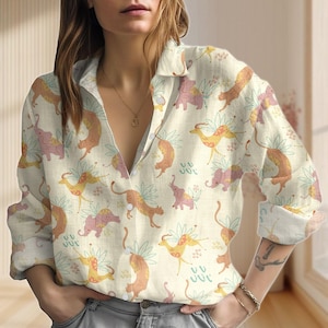May include: A cream-colored button-down shirt with a repeating pattern of stylized animals, including elephants and leopards, in shades of pink, orange, and yellow. The shirt has long sleeves and a collared neckline.