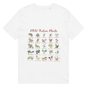 Peut inclure: T-shirt blanc avec une illustration botanique de plantes indigènes du nord-ouest du Pacifique. Le motif comprend diverses baies et plantes avec leurs noms et le texte "PNW Native Plants" en écriture cursive.