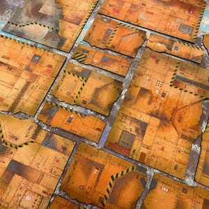 Peut inclure: Un ensemble de dalles de sol industrielles plates aux tons orange, présentant une texture métallique usée avec des motifs de grille, des rivets et des bandes de danger jaunes et noires. Plusieurs pièces portent des numéros blancs, dont 21, 47, 79, 90 et 180.