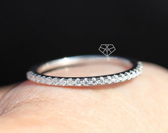 May include: A thin silver band with a row of small, clear diamonds set in a pave setting.