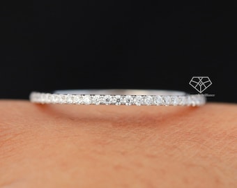 May include: A thin silver band with a row of small diamonds set in a pave setting.