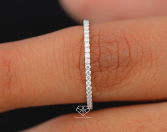 May include: A thin, silver band with a row of small, clear diamonds set in a pave setting.