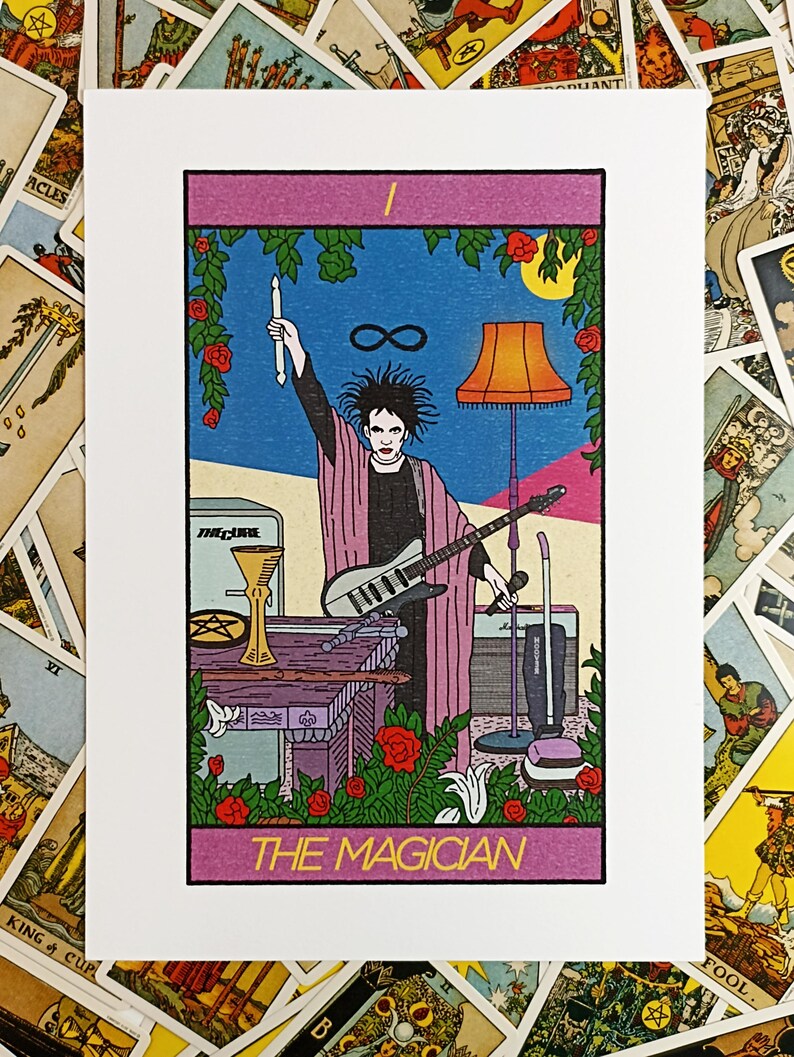 May include: A rectangular art print featuring a tarot card illustration titled THE MAGICIAN. The image depicts a person with dark hair holding a drumstick and microphone, wearing a pink robe, standing behind a table with a guitar and objects.