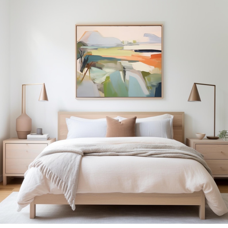 K&ouml;nnte beinhalten: Ein Bett mit einem hellen Holzrahmen, einer wei&szlig;en Bettdecke und einer beigefarbenen Wolldecke. Das Bett hat zwei wei&szlig;e Kissen und ein braunes Kissen. &Uuml;ber dem Bett h&auml;ngt ein gerahmtes abstraktes Landschaftsbild.