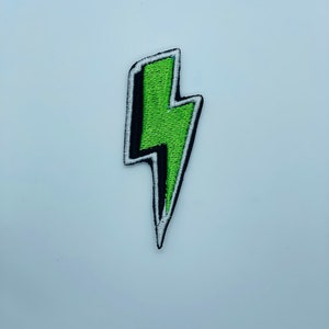 May include: A green lightning bolt patch with a white outline and black stitching.