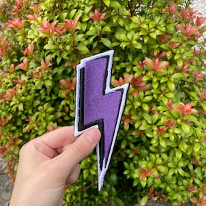 May include: Purple lightning bolt shaped iron-on patch with white and black outlines.
