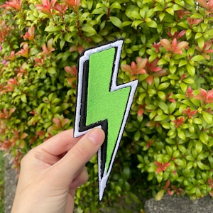 May include: Green lightning bolt shaped iron-on patch with white and black outlines.