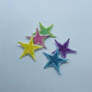 Peut inclure: Cinq patchs brodés en forme d'étoile dans différentes couleurs pastel, dont le jaune, le rose, le vert, le violet et le bleu.