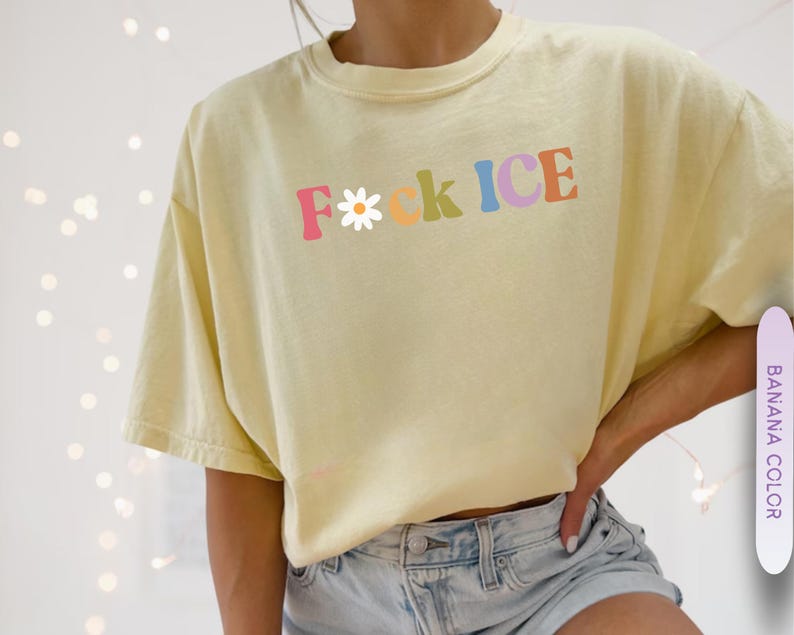 May include: A light yellow t-shirt with the text "F*ck ICE" in colorful letters. The "F" is a daisy, and the shirt is paired with denim shorts. The shirt is a banana color.
