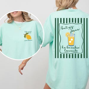 May include: A light green t-shirt with a lemon graphic and the text "life gave me some lemons" on the front. The back of the shirt has a lemonade graphic and the text "but my Jesus he be makin' lemonade".