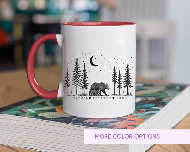 May include: White ceramic mug with a red interior and handle. The mug features a black and white illustration of a bear and cub in a forest under a crescent moon and stars. The names Olivia, Allison, and Axel are printed below the image.