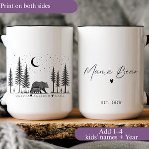 May include: White ceramic mug with a black handle and rim. One side features a bear and cub in a forest scene with names below. The other side says "Mama Bear" with a heart and "EST. 2025".