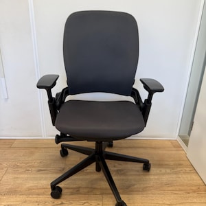 Op de afbeelding: Een zwarte bureaustoel met een grijze mesh rugleuning en zitting. De stoel heeft verstelbare armleuningen en een vijfsterrenvoet met wielen.