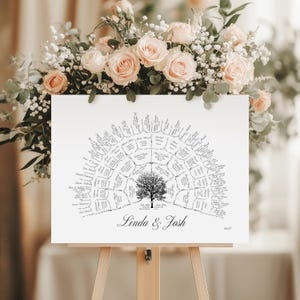 Peut inclure: Un plan de table de mariage blanc avec un motif d'arbre et les noms des invit&eacute;s dispos&eacute;s en demi-cercle. Les noms "Linda & Josh" sont &eacute;crits en dessous de l'arbre. Le panneau est pr&eacute;sent&eacute; sur un chevalet en bois, avec des fleurs en arri&egrave;re-plan.