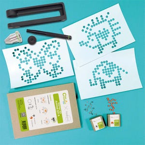 Peut inclure: Un kit d'artisanat pour réaliser des mosaïques d'animaux. Le kit comprend deux gabarits blancs avec des trous pré-percés, un outil noir, un outil argenté, un marqueur noir, deux contenants de perles colorées et une boîte brune avec le texte "Starter Kit Animal Kit A" imprimé dessus.
