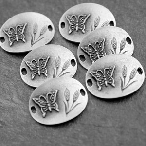 Puede incluir: Seis abalorios ovalados de plata con un diseño de mariposa y trigo. Cada abalorio tiene dos agujeros para sujetarlo a una pulsera o collar.
