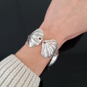 Può includere: Bracciale in argento con un design di maglie sovrapposte a forma di foglia testurizzata.