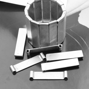 Könnte beinhalten: Ein Satz silberner magnetischer Verschlüsse aus Metall, einige sind kreisförmig, andere rechteckig. Die Verschlüsse befinden sich auf einer schwarzen Oberfläche.