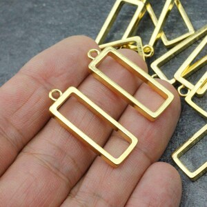 May include: Gold-toned metal rectangular frames with a loop at the top. These frames are ideal for resin crafts and jewellery making.