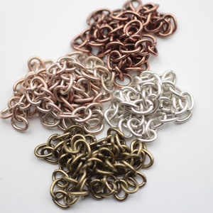 Pode incluir: Quatro pilhas de corrente metálica em diferentes cores: cobre, ouro rosa, prata e latão.