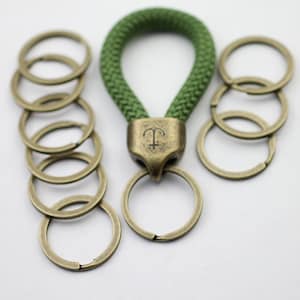 Può includere: Un portachiavi in corda verde con un ciondolo a forma di ancora e più anelli per chiavi in ottone.