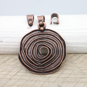 Op de afbeelding: Een koperkleurige hanger met een spiraalvormig ontwerp. De hanger is bevestigd aan een springring en wordt geleverd met twee koperkleurige sluitingen.