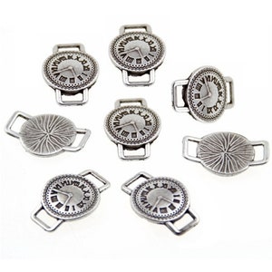 Puede incluir: Ocho abalorios de metal plateado en forma de esfera de reloj con un bucle a cada lado. Los abalorios están diseñados para ser utilizados como abalorios para zapatos o bolsos.