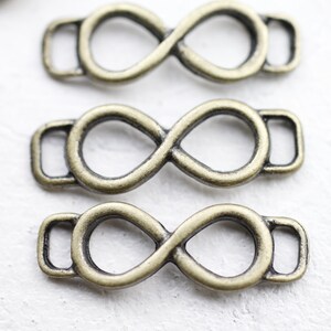 May include: Three antique gold-toned infinity symbol metal clasps with a loop on each side.