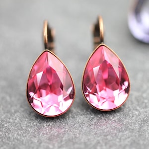 Puede incluir: Un par de pendientes de cristal rosa en forma de lágrima con un engaste de metal de tono cobre.