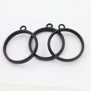 May include: Three black metal circle pendants with a small loop at the top for hanging. The pendants are evenly spaced against a white background. These are ideal for jewelry making or craft projects.