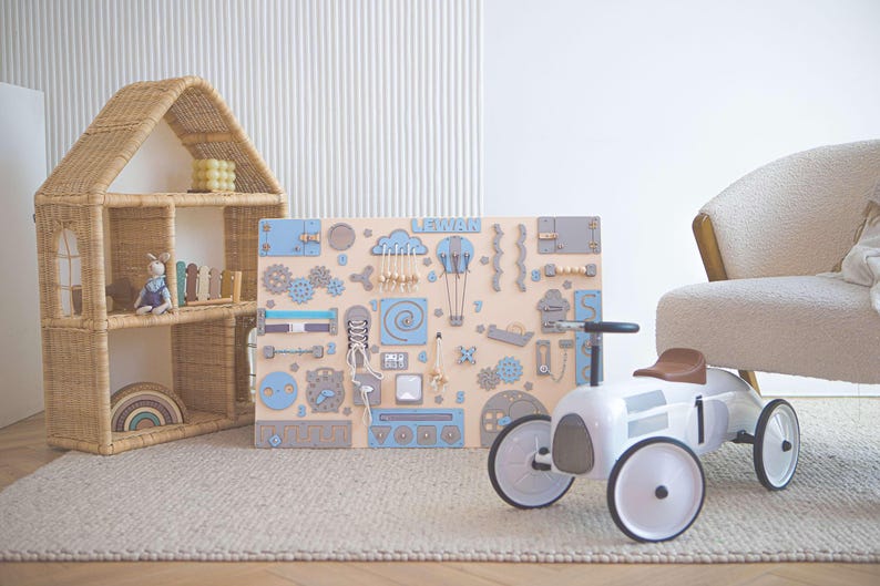 A large blue activity board for toddler with mazes, a sorter, doors and other play elements.