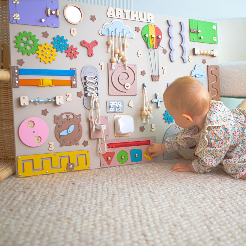 The toddler arranges figures in various shapes on a colourful Montessori manipulative board.