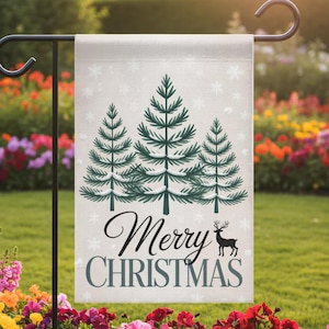May include: A rectangular garden flag with a light gray background features three green Christmas trees with snow accents. The words "Merry Christmas" are written in black script and gray block letters, with a black reindeer silhouette. White snowflakes are scattered across the flag.