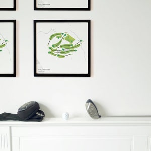 May include: A black framed print of a golf course map with the text "GOLF MEGGDEN" in white. A golf club, golf ball, and a golf glove are on a white shelf.