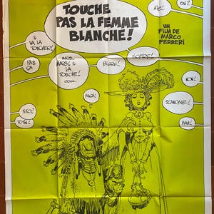 May include: A yellow poster with black text and illustrations. The text reads "Touche Pas La Femme Blanche!" and "Un Film de Marco Ferreri". The poster features a cartoon image of a Native American man and a woman in a long dress.