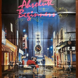 Pode incluir: Um cartaz de filme para a comédia musical "Absolute Beginners" ambientada em uma rua de Londres chuvosa à noite. O cartaz apresenta um casal dançando na rua, com uma grande torre do relógio ao fundo. O título do filme está escrito em letras rosa e amarelas.